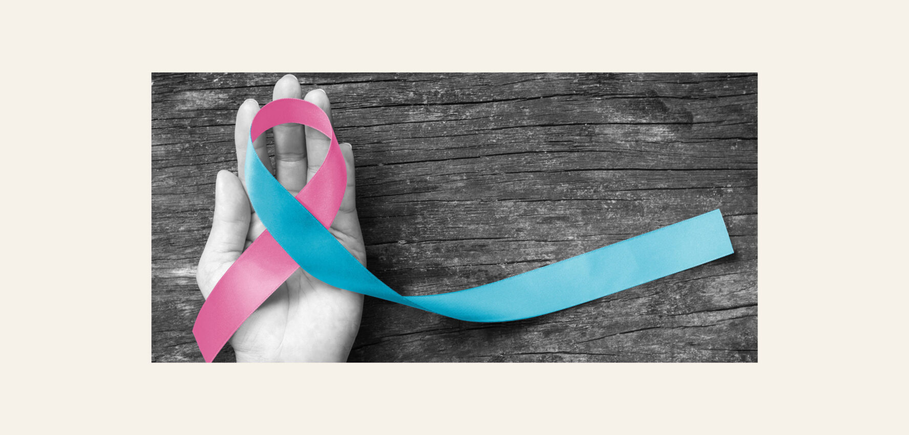 A woman holds a pink and blue ribbon in her hand