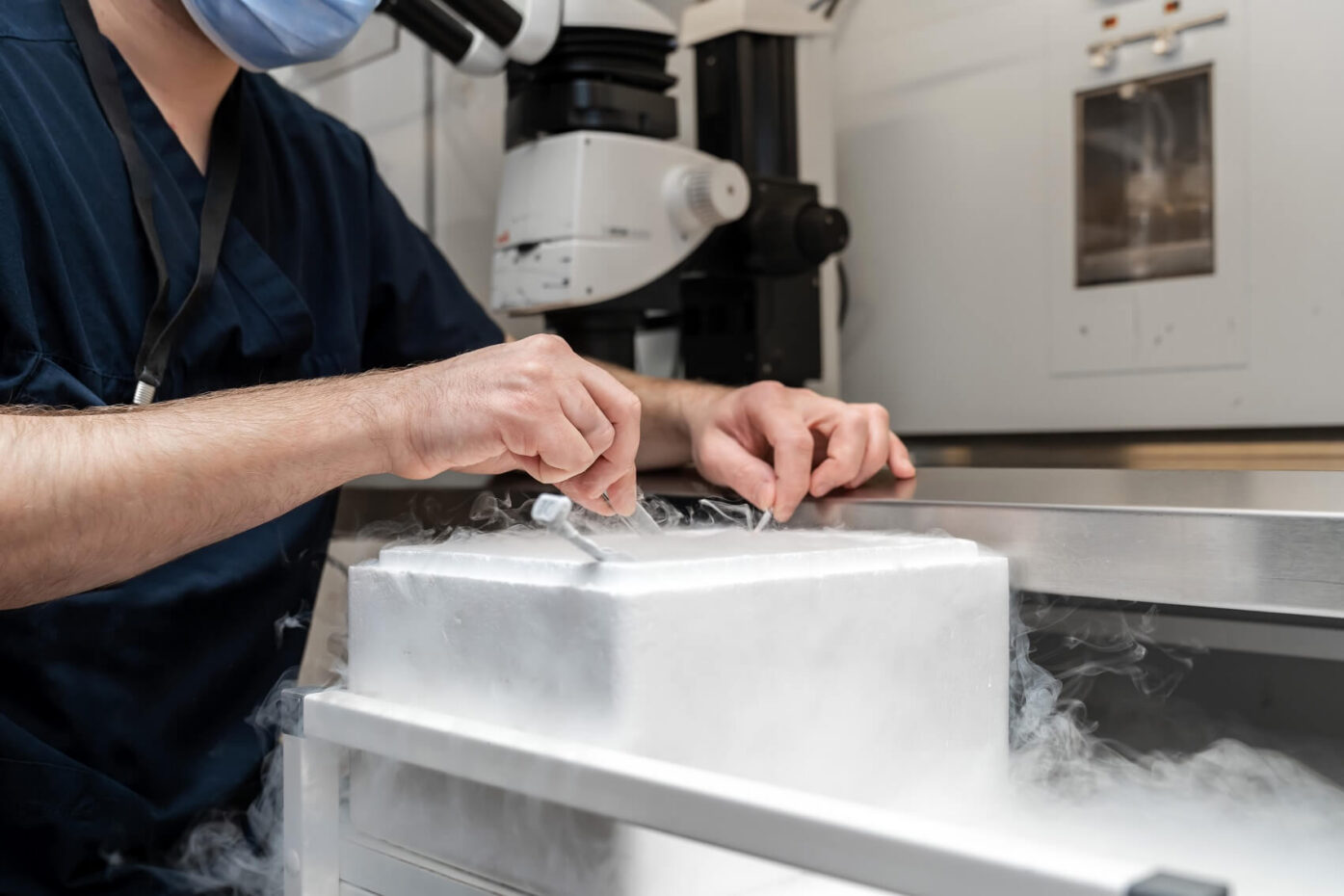 A doctor in dark blue scrubs carefully handles a frozen egg