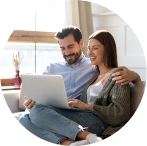 A man and woman smile while sitting together and looking at a laptop