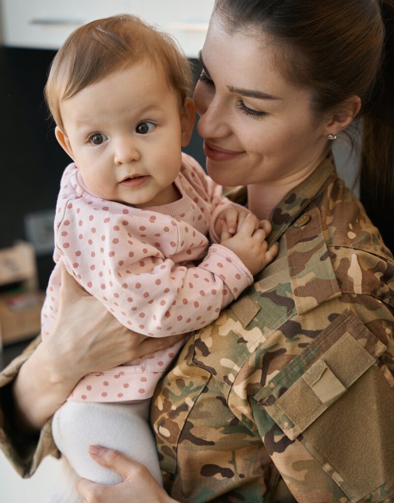 Young military woman holds a little girl in her arms, a mother in a camouflage uniform